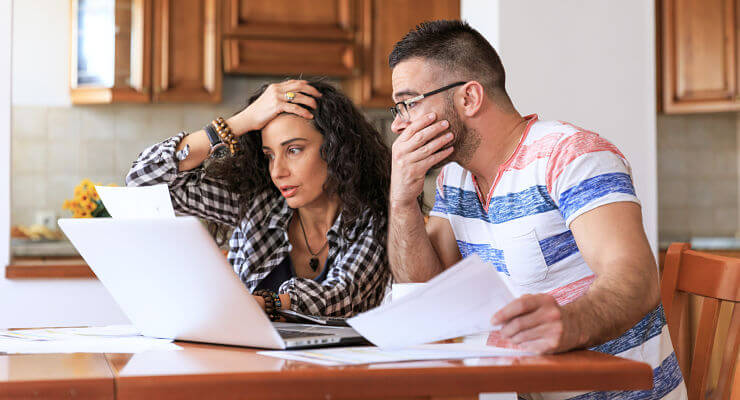 Un couple inquiet regarde ses factures et ses comptes