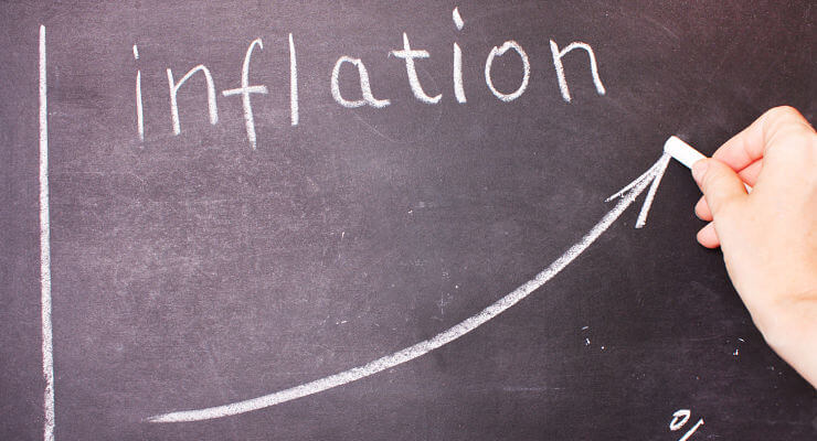 Une jeune femme écrit le mot « Inflation » sur un tableau noir