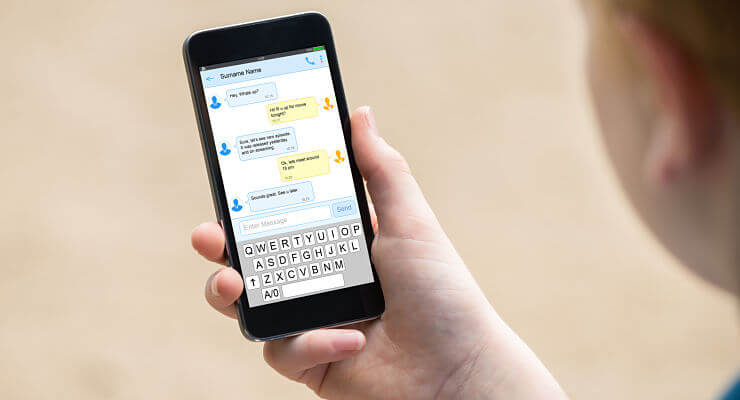Une personne tient son smartphone dans la main et regarde une conversation par sms
