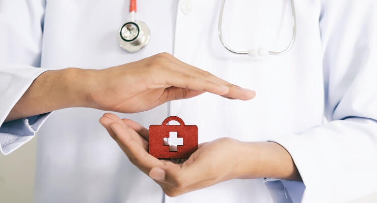 Une médecin tient entre ses mains une petite malette de soins rouge 