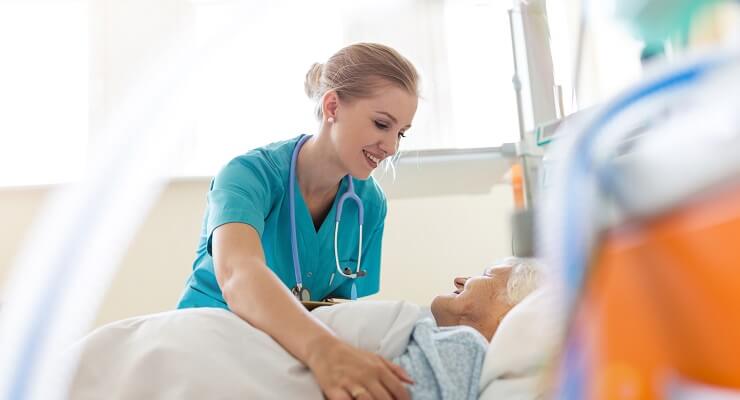 Une infirmière borde une personne âgée dans un lit d'hôpital