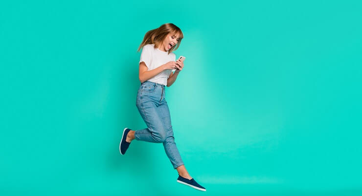 Femme sautant de joie avec son téléphone portable dans les mains